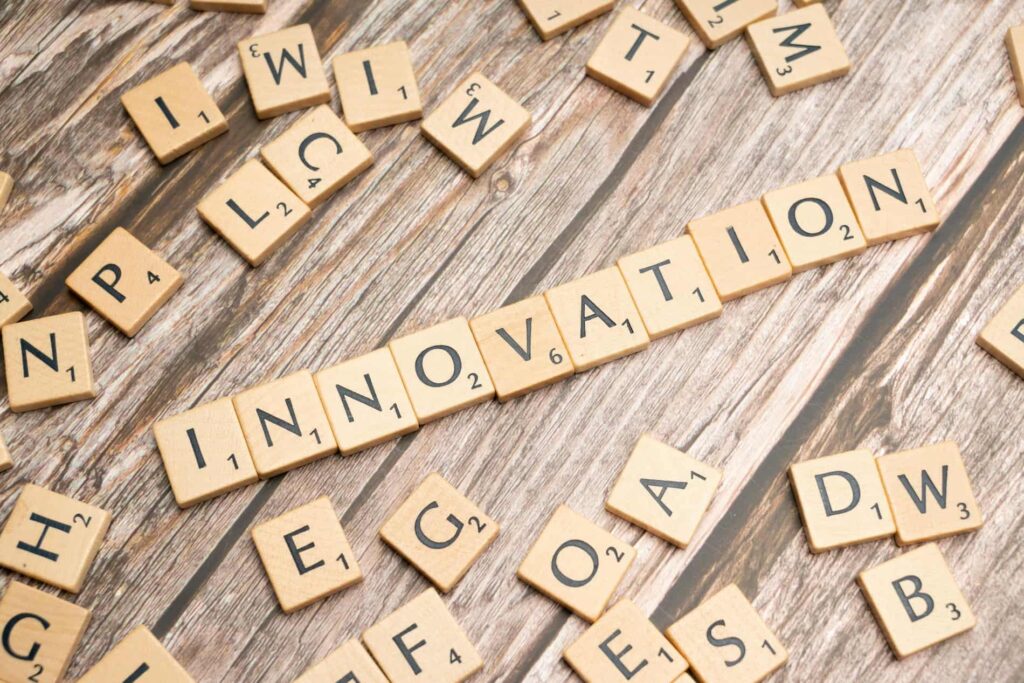 Дерев'яні плитки з літерами на дерев'яному фоні складають слово INNOVATION (Інновація); навколо розкидані інші літери; ілюстрація до Всесвітнього дня творчості та інноваційної діяльності 21 квітня.