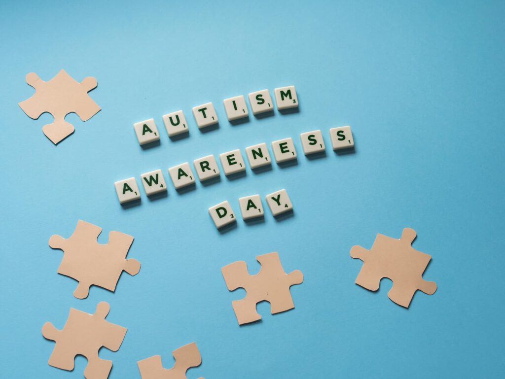 Напис Autism Awareness Day з кубиків на блакитному фоні Напис Autism Awareness Day з кубиків на блакитному фоні з елементами пазлів, вид зверху, концепція до Дня поширення інформації про аутизм.