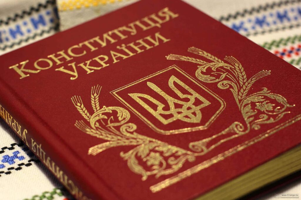 Крупний план книги Конституція України в твердій темно-червоній обкладинці із золотим тисненням державного герба