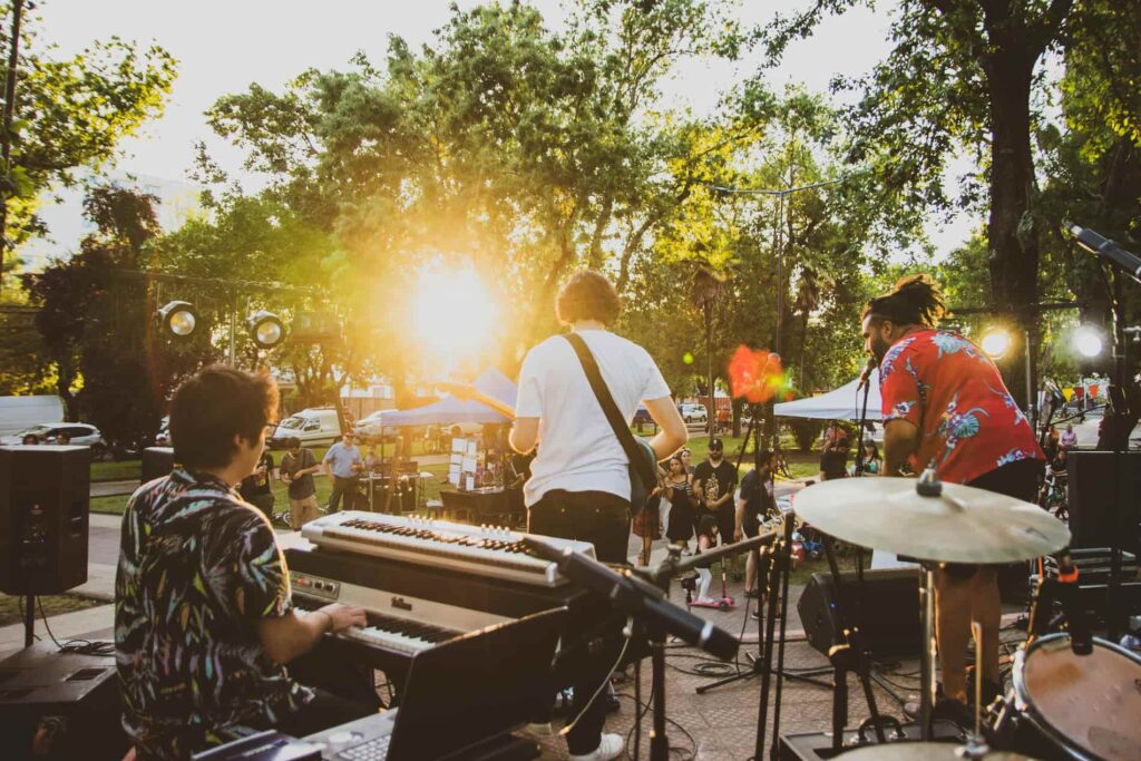 Make Music Day Музичний гурт виступає на відкритій сцені в парку під час заходу сонця.