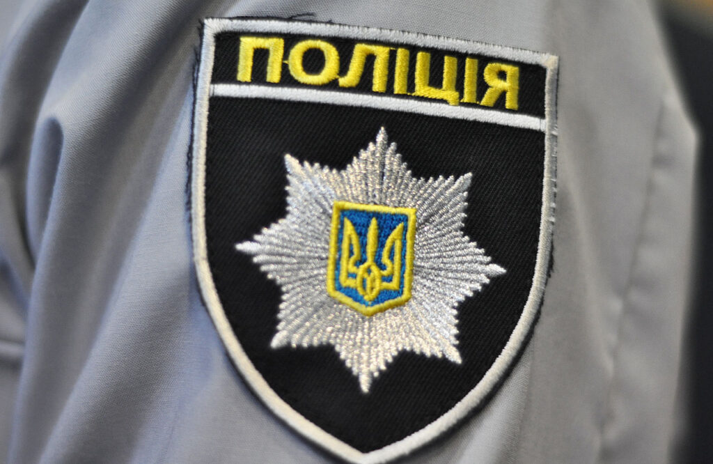 Крупний план нарукавного знака (шеврона) Національної поліції України у формі щита із жовтим написом «Поліція»